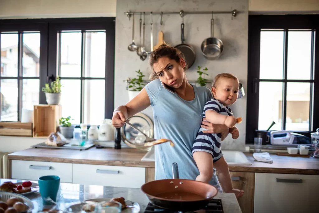 Mother Holding Baby while cooking dinner